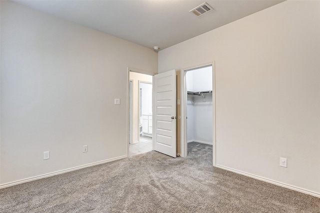 unfurnished bedroom with a walk in closet and carpet