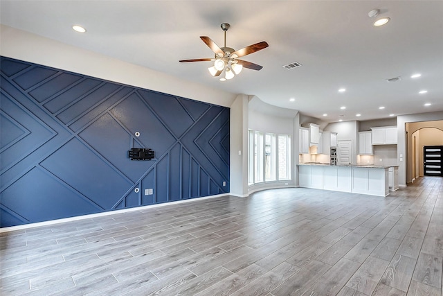 unfurnished living room featuring ceiling fan and light wood-type flooring