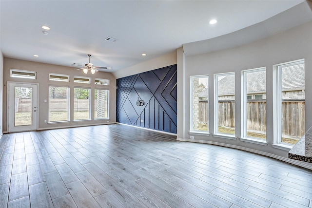 unfurnished room with light hardwood / wood-style flooring, a barn door, and ceiling fan