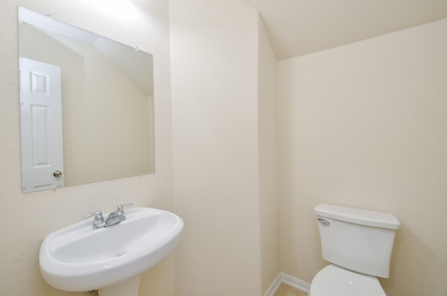 bathroom with lofted ceiling, toilet, and sink