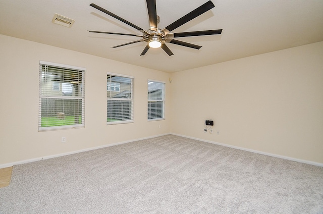 empty room featuring ceiling fan, light colored carpet, and a healthy amount of sunlight