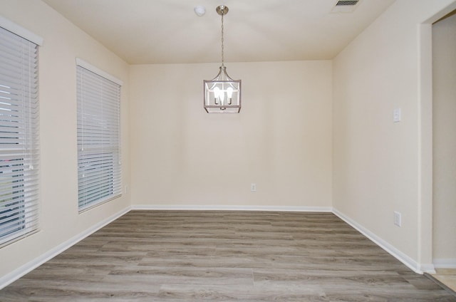 unfurnished dining area with an inviting chandelier and hardwood / wood-style floors