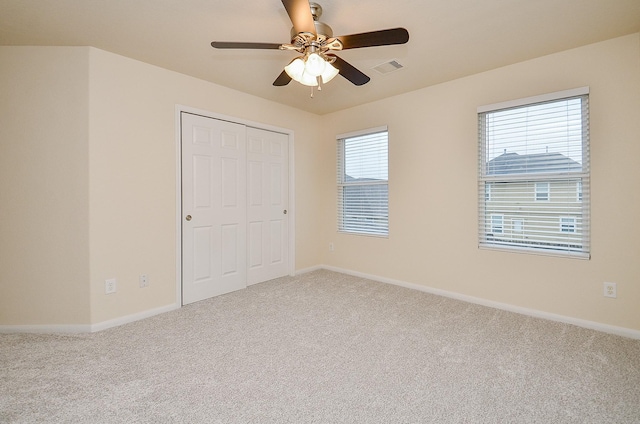 unfurnished bedroom with light colored carpet, ceiling fan, and a closet