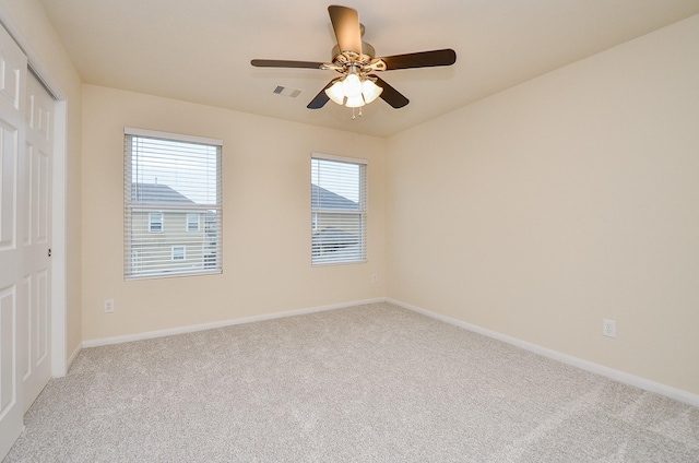 empty room with ceiling fan and light carpet