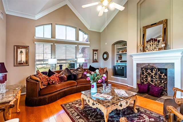 living room featuring built in shelves, ornamental molding, wood-type flooring, and a tiled fireplace