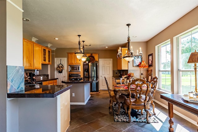 kitchen with an inviting chandelier, appliances with stainless steel finishes, decorative light fixtures, and plenty of natural light