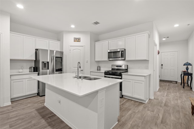 kitchen with sink, white cabinetry, light hardwood / wood-style flooring, an island with sink, and stainless steel appliances