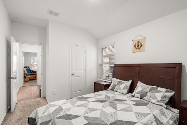 bedroom with lofted ceiling, light carpet, and a closet