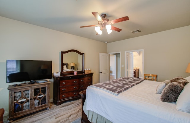 bedroom with a ceiling fan, ensuite bath, visible vents, and wood finished floors