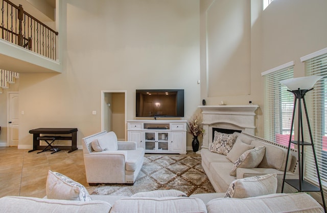 living room featuring light tile patterned floors, a high ceiling, a fireplace, and baseboards