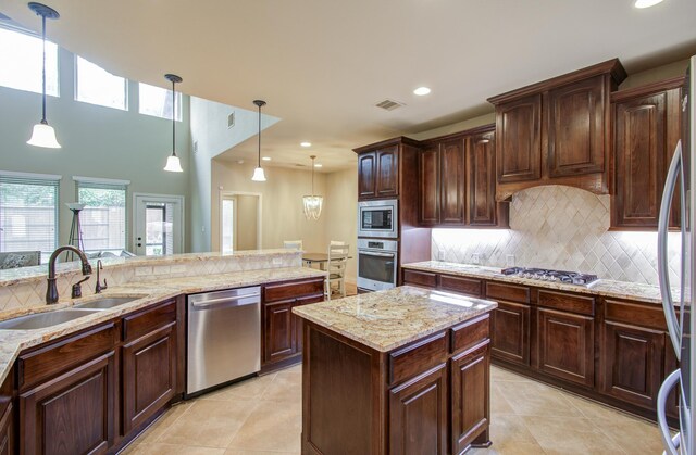 kitchen with appliances with stainless steel finishes, pendant lighting, tasteful backsplash, sink, and dark brown cabinetry