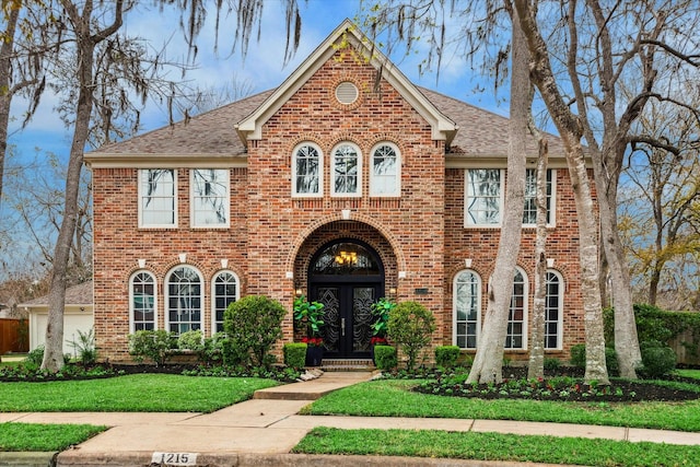 view of front of house featuring a garage, a front yard, and french doors