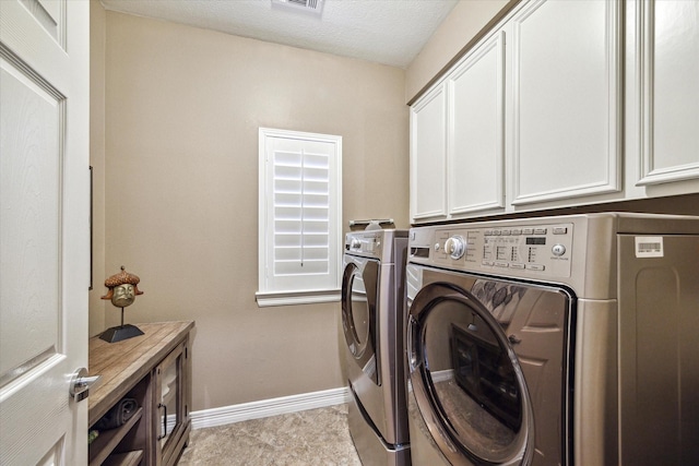 laundry room featuring cabinets, washing machine and clothes dryer, and a textured ceiling