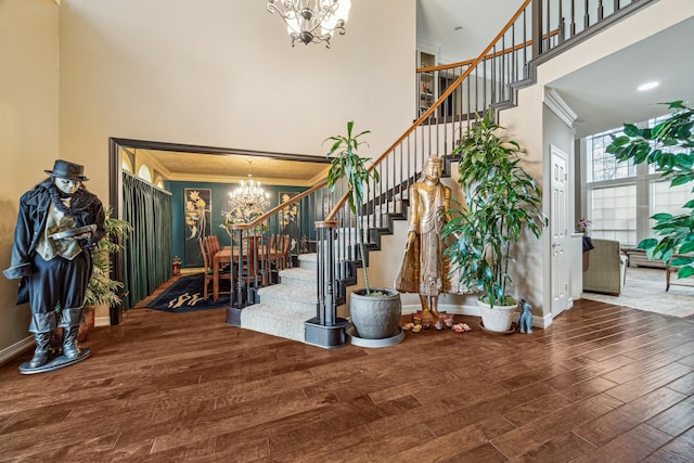 foyer entrance featuring an inviting chandelier, hardwood / wood-style floors, crown molding, and a high ceiling