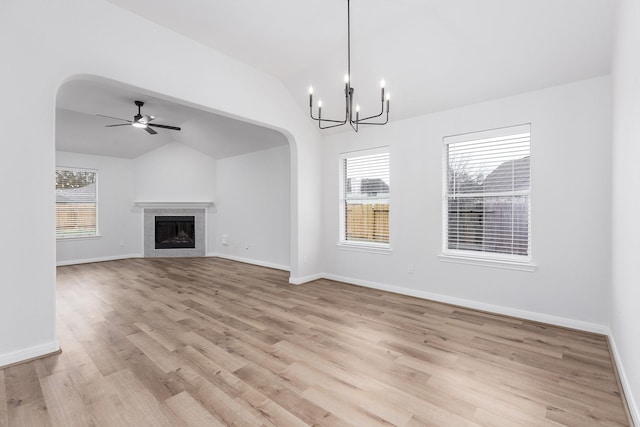 unfurnished living room featuring vaulted ceiling, ceiling fan with notable chandelier, and light hardwood / wood-style floors