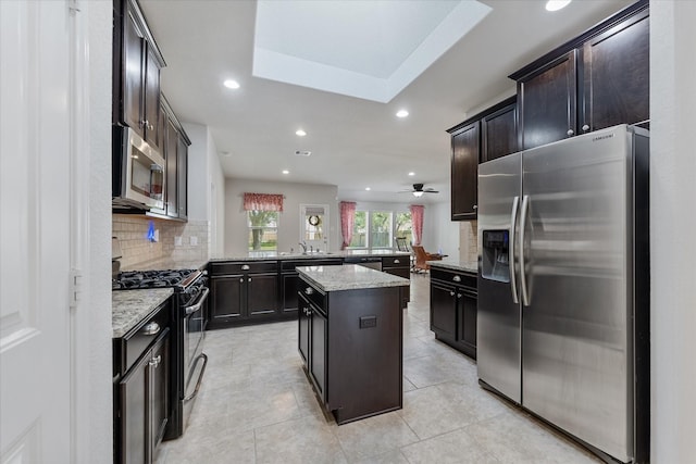 kitchen featuring appliances with stainless steel finishes, tasteful backsplash, light stone counters, a kitchen island, and kitchen peninsula