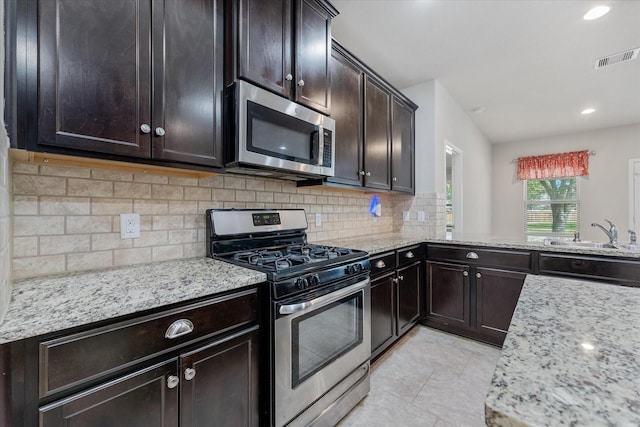 kitchen featuring sink, backsplash, light stone countertops, and appliances with stainless steel finishes