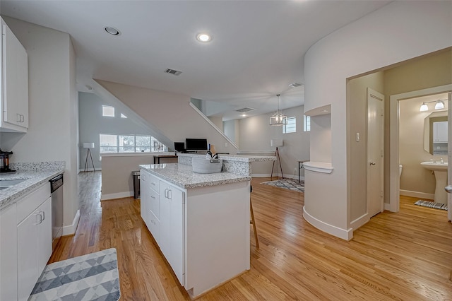 kitchen with white cabinetry, a kitchen island, stainless steel dishwasher, and pendant lighting