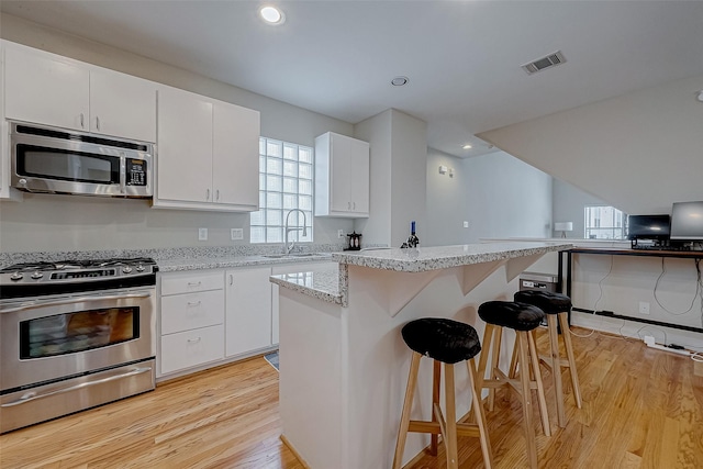 kitchen featuring a breakfast bar area, white cabinets, and appliances with stainless steel finishes