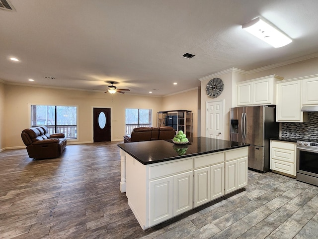 kitchen featuring white cabinetry, backsplash, stainless steel appliances, wood-type flooring, and a kitchen island