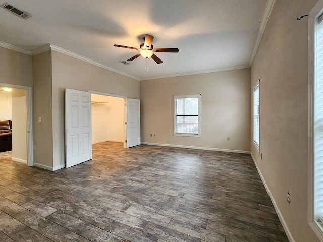 unfurnished bedroom with a walk in closet, ornamental molding, dark hardwood / wood-style flooring, a closet, and ceiling fan