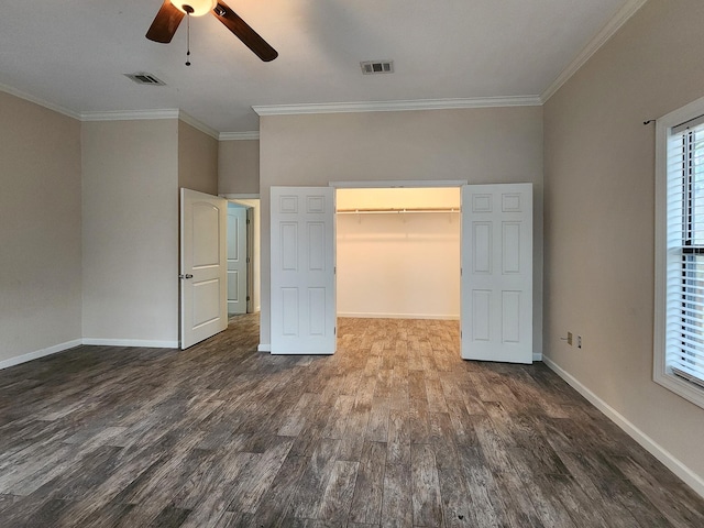 unfurnished bedroom with crown molding, dark wood-type flooring, a closet, and a spacious closet