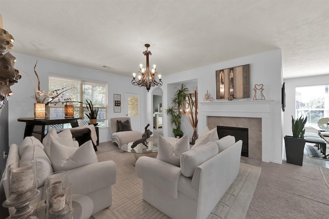 living room featuring a tiled fireplace, light colored carpet, and a notable chandelier