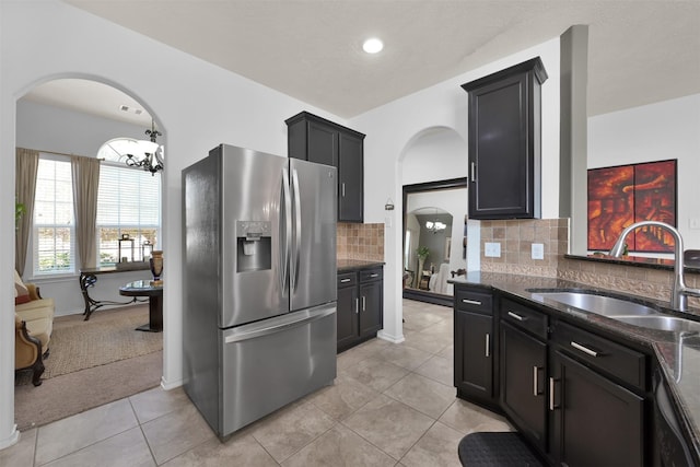 kitchen with tasteful backsplash, sink, stainless steel fridge, a chandelier, and light tile patterned floors