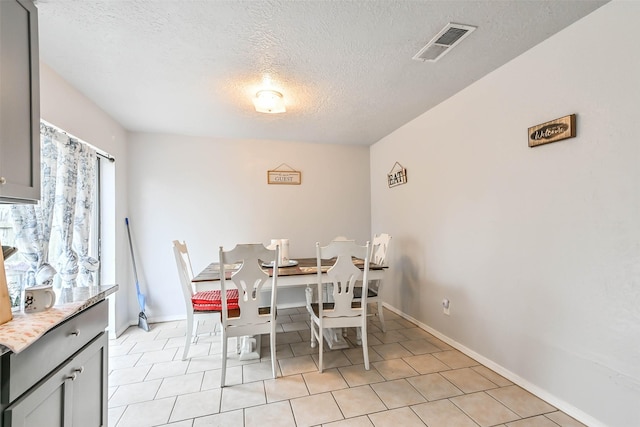 tiled dining room featuring a textured ceiling