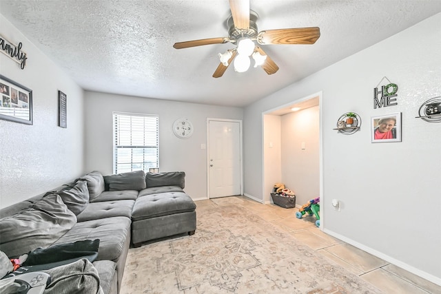 living room with ceiling fan, a textured ceiling, and light tile patterned floors