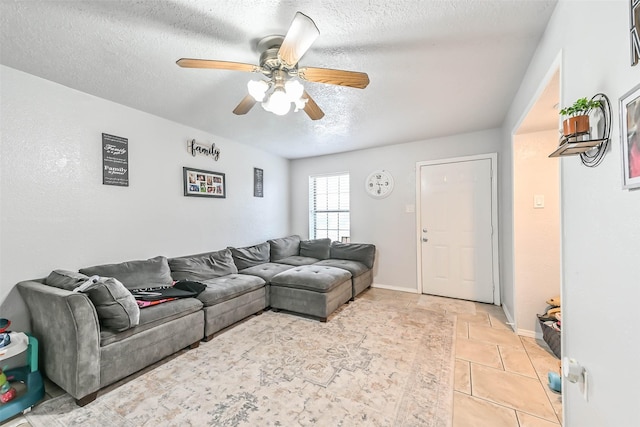 living room featuring ceiling fan, light tile patterned floors, and a textured ceiling