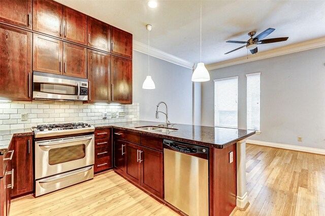 kitchen with appliances with stainless steel finishes, sink, pendant lighting, and kitchen peninsula