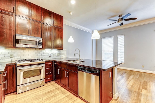 kitchen with pendant lighting, sink, stainless steel appliances, and kitchen peninsula