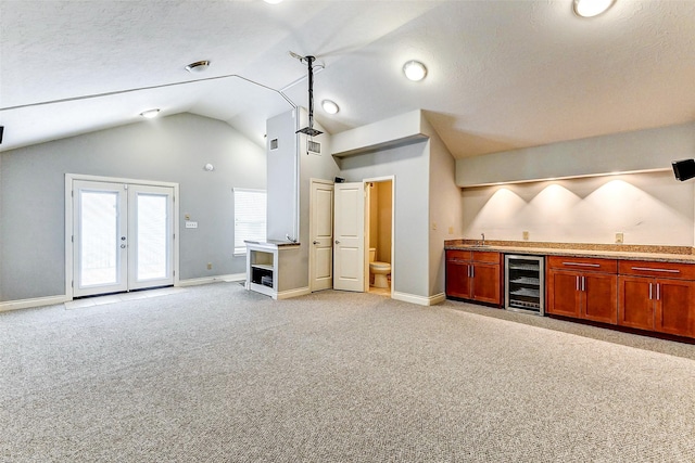 kitchen with lofted ceiling, sink, wine cooler, light colored carpet, and a textured ceiling