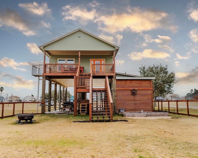 back of property with an outdoor fire pit and a yard