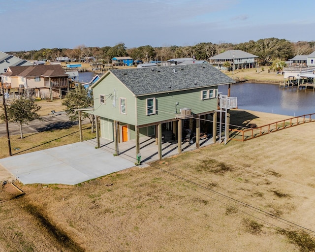 rear view of house with a yard, a garage, and a water view