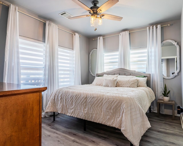 bedroom featuring ceiling fan, hardwood / wood-style floors, and multiple windows