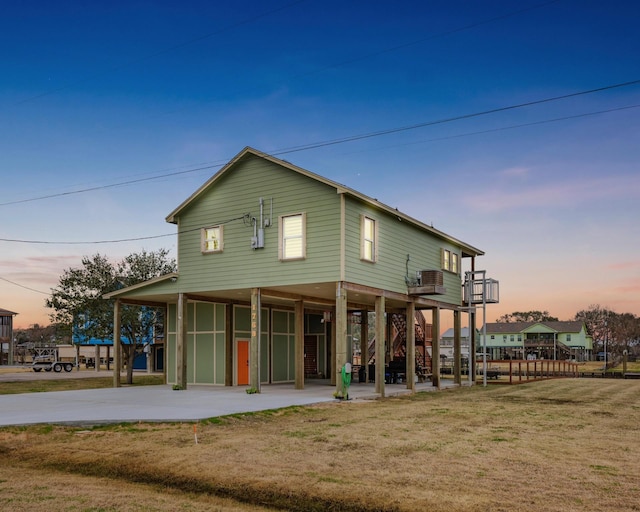 back house at dusk with a yard and a carport