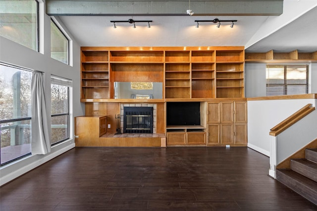 unfurnished living room featuring a tile fireplace, vaulted ceiling with beams, and dark wood-type flooring