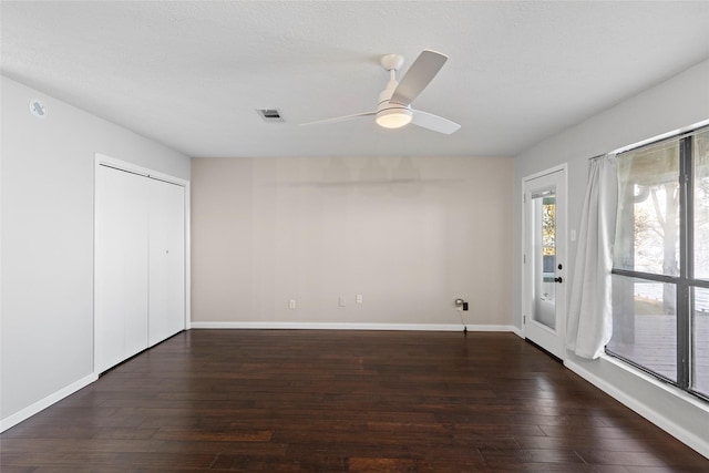 unfurnished bedroom with dark wood-type flooring, a closet, and ceiling fan