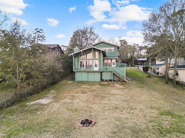 rear view of house with a yard, a deck, and an outdoor fire pit