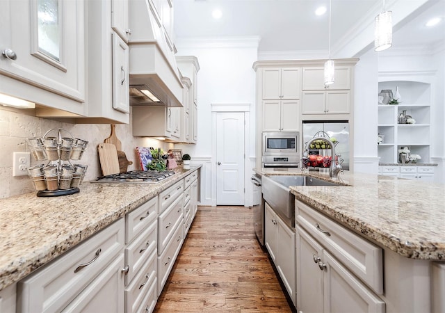 kitchen with tasteful backsplash, pendant lighting, stainless steel appliances, light stone countertops, and white cabinets