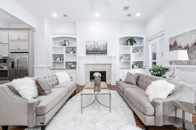 living room featuring crown molding, built in features, ceiling fan, and light wood-type flooring