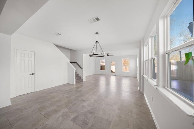 unfurnished living room featuring a chandelier