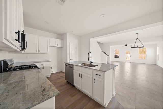 kitchen with sink, white cabinetry, range, stainless steel dishwasher, and a kitchen island with sink