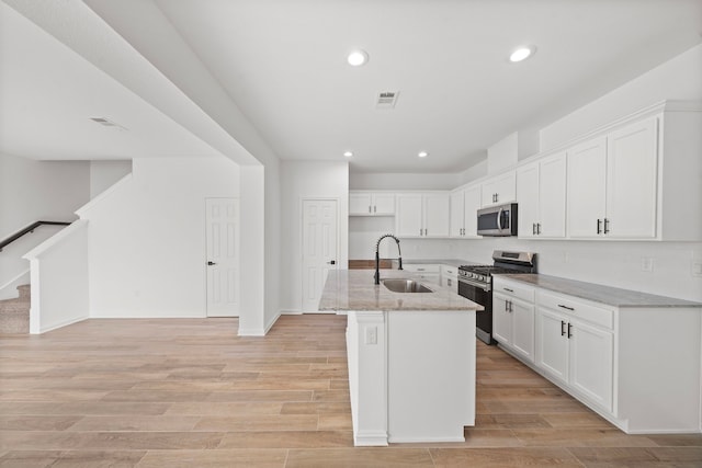 kitchen featuring white cabinetry, sink, light stone countertops, and appliances with stainless steel finishes