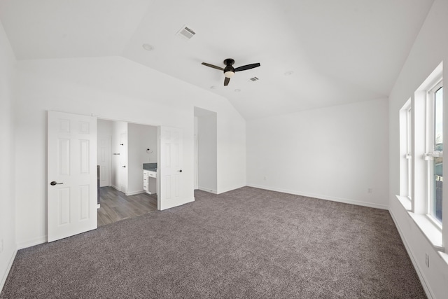 unfurnished bedroom featuring ceiling fan, vaulted ceiling, and dark colored carpet