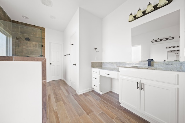 bathroom with vanity, hardwood / wood-style flooring, and tiled shower