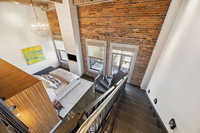 interior space with a towering ceiling, brick wall, and a chandelier