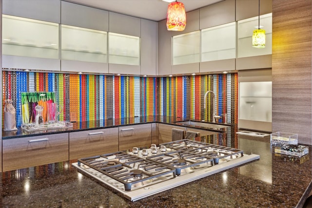 details with dark stone countertops, sink, decorative light fixtures, and stainless steel gas cooktop